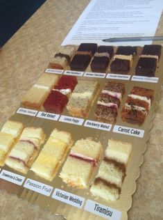 a table topped with lots of different types of cakes next to a paper sign that says carrot cake