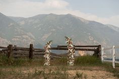 two wreaths with flowers on them are placed in front of a fence and mountains