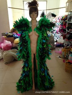 a mannequin dressed in green and blue feathers is standing in a room full of clothes