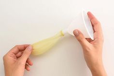 two hands are holding a plastic cone with something yellow on the top and one hand is pulling it up