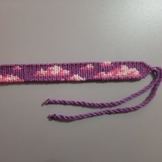 a close up of a piece of fabric with flowers on it and purple string attached to the end