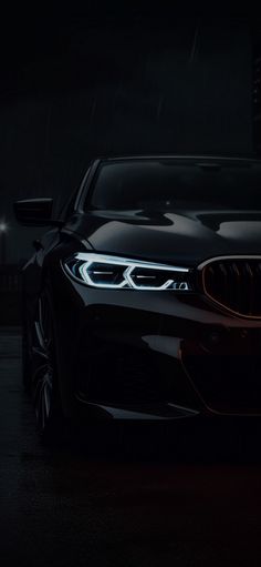 the front end of a black bmw car at night