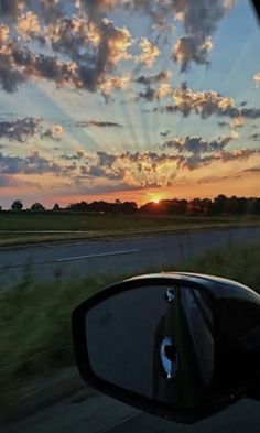 the sun is setting in the distance as seen from a car's side view mirror