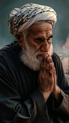 an old man sitting down with his hands clasped to his face while looking at the camera