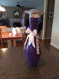 a purple vase with a white ribbon on it sitting on top of a granite counter