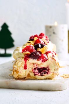 a pastry with fruit on it sitting on top of a white counter next to a lit candle