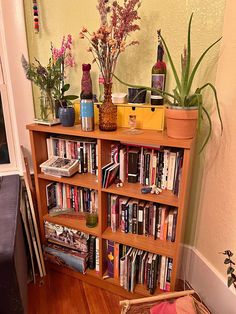 a bookshelf filled with lots of books next to a planter and potted plants