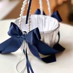 a white and blue basket with pearls hanging from it's side on a table