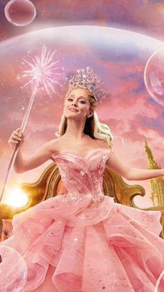 a woman in a pink dress holding a wand and wearing a tiara with bubbles floating around her