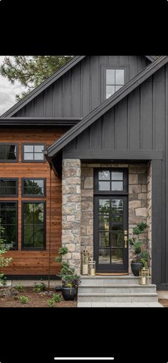 the front entrance to a house with black doors and stone steps leading up to it