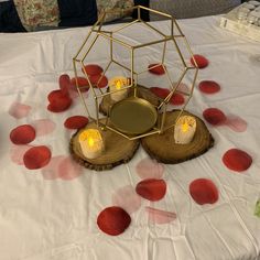 a table with red petals on it and a candle holder in the center surrounded by candles