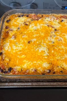 a casserole dish with cheese and black olives in it sitting on top of an oven