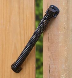 a black hose is attached to the side of a wooden fence with a screwdriver