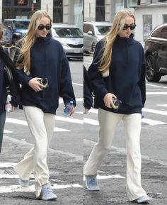 two women walking down the street in white pants and blue sweaters, both carrying water bottles