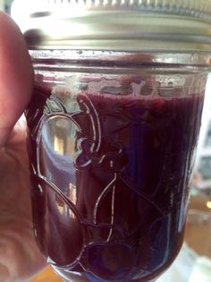 a hand holding a jar filled with purple liquid