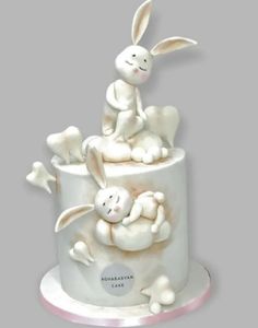 a cake decorated with white frosting and bunny figurines sitting on top of it