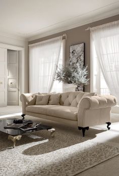 a living room filled with furniture and white drapes on the window sills