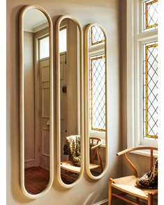 a large mirror sitting on the side of a wall next to a chair and window