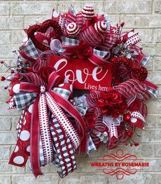 the wreath is decorated with red, white and black ribbons that read love lives here