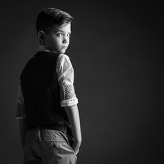 a young boy is posing for a black and white photo with his hands in his pockets