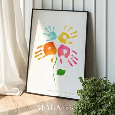 an art print with hand prints on it next to a potted plant