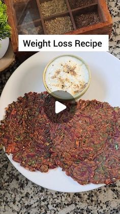 a white plate topped with lots of food next to a bowl of dip and tray of seeds