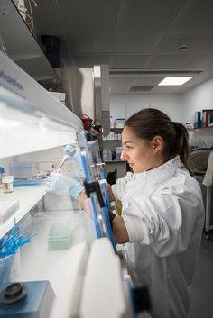 a woman in a lab coat is looking at something on a shelf with blue handles