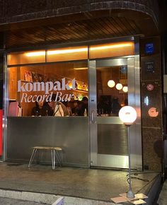 the front entrance to kompak record bar at night with people sitting in it