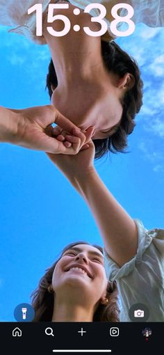 two people reaching up to touch each other's hands with the sky in the background