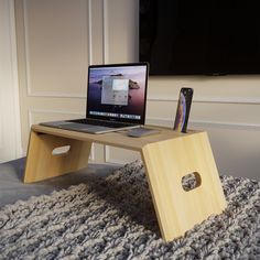 an open laptop computer sitting on top of a wooden table next to a cell phone