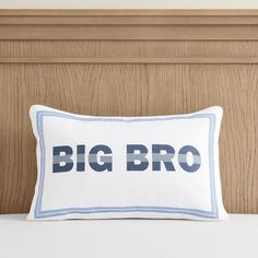 a white pillow with the words big bro printed on it sitting on a wooden headboard