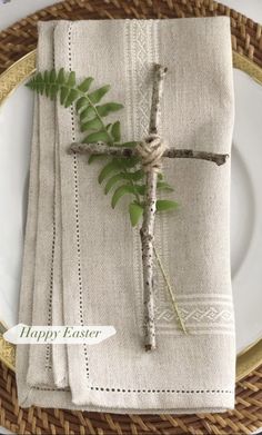 a place setting with white plates and napkins on top of each other, decorated with green leaves