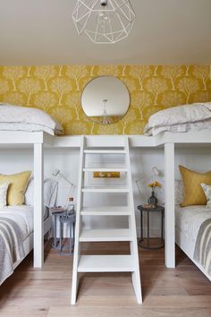 two white bunk beds with yellow pillows in a bedroom on instagram, one has a ladder and the other has a mirror above them