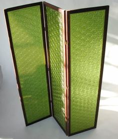 a green room divider sitting on top of a white floor next to a potted plant