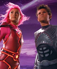 two young people in futuristic clothing standing next to each other with the sky and clouds behind them