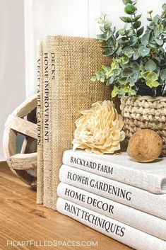 a stack of books sitting on top of a wooden table next to a potted plant