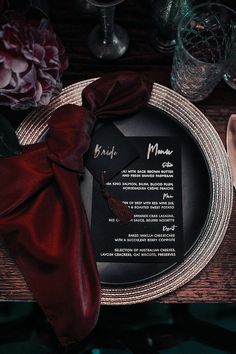 a plate with a menu on it sitting next to a red napkin and some flowers