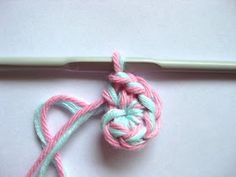 a crochet knot is laying on top of a white surface next to a knitting needle