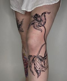 a woman's legs with tattoos on them and flowers in the middle of her leg