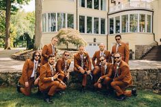 a group of men in brown suits and ties posing for a photo on the grass