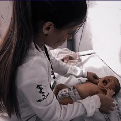 a woman is holding a baby doll in her lap and looking down at it's head