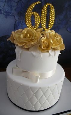 a white cake with gold flowers and the number 60 on it's top tier