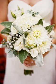 a bride holding a bouquet of white flowers