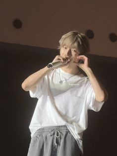 a young man holding a microphone up to his mouth while standing in front of a stage