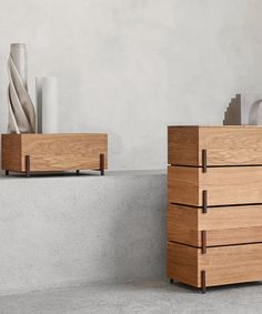 two wooden drawers sitting next to each other on top of a cement floor with vases in the background