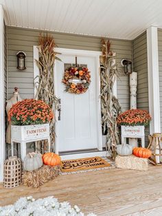 the front porch is decorated for fall with pumpkins and cornstatch wreaths