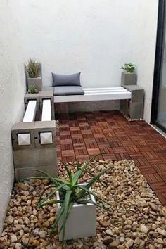 a small patio with some plants and rocks on the ground next to it, along with a bench