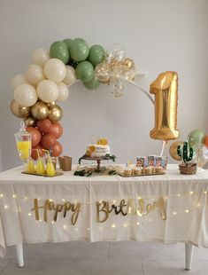 a table topped with balloons and cake next to a number one sign