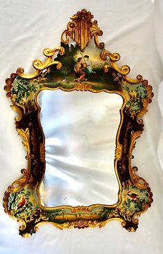 an ornately decorated mirror is hanging on a white cloth covered wall with gold trimmings