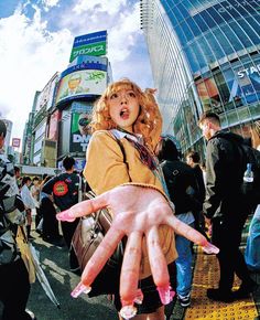 a woman with her hands painted pink in the middle of a crowded city street as people walk by